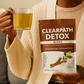 Person holding a package of Clearpath Detox Blend tea and a glass of tea.